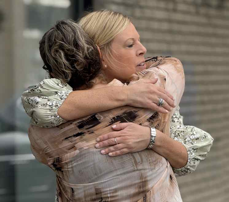 Vehicle donor and recipient embracing at award ceremony.